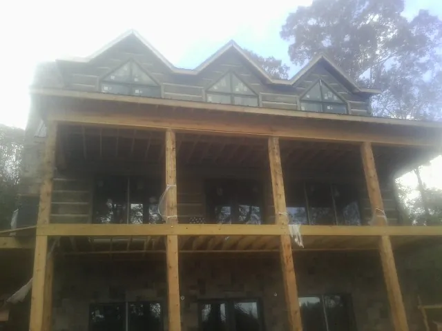 Dormers and porch framing on a large log home under construction — Roof Coating work by our crew in Granite Canon