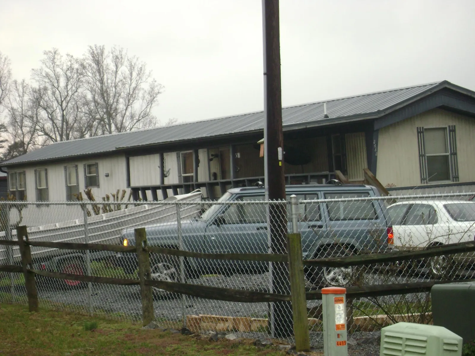 Dark metal roof on a long single story building behind a chain link fence in Granite Canon