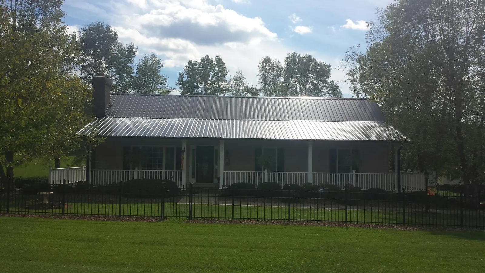 Gray metal roof on a brick ranch with a full width front porch — Gutter Guard Installation work by our crew in Granite Canon