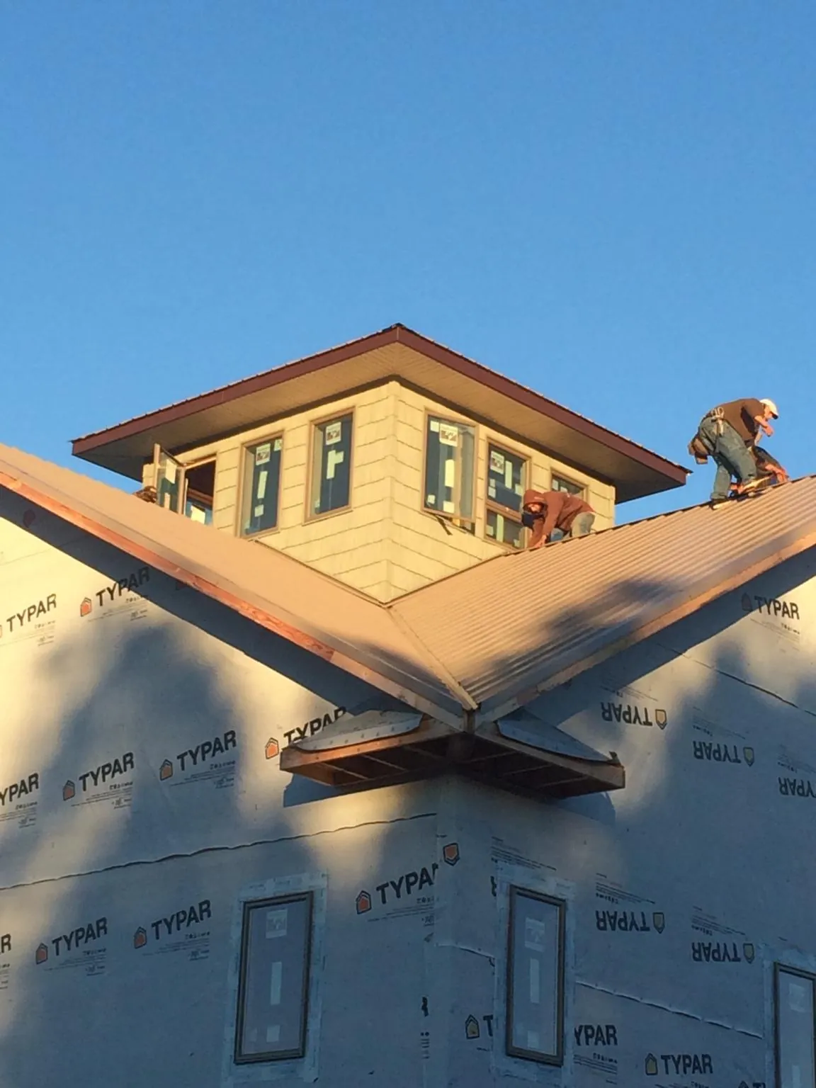 Roofers working around a rooftop cupola on a new metal roof at sunset — Roof Waterproofing in Granite Canon by Roofing Brothers